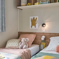 Mobil Home Aqua 3 Chambres 6 Personnes Terrasse semi-couverte TV - Camping La Vallée des Vignes : chambre avec lits, peluche et lampe murale