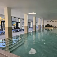 Piscine intérieure avec chaises longues et colonnes dans un camping.