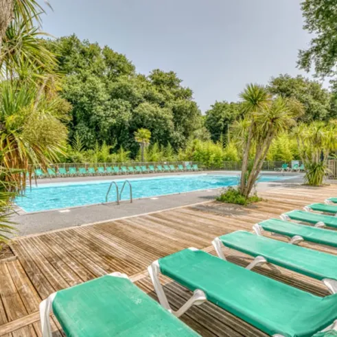 Piscine entourée de chaises longues vertes Camping La Clairière