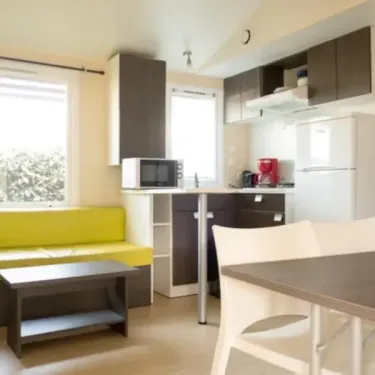 Mobil Home Eco 3CH - cuisine et salon avec canapé jaune, table et réfrigérateur