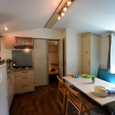 Intérieur du mobil home avec cuisine, table et lit - Les Salisses