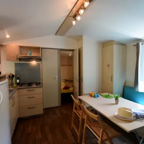 Intérieur du mobil home avec cuisine, table et lit - Les Salisses