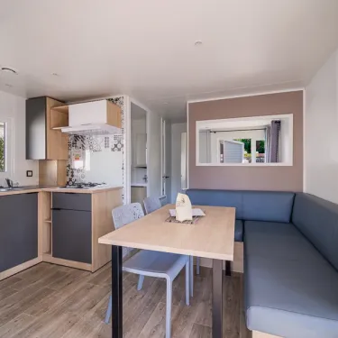 Salle à manger et cuisine du mobil home Le Paradis, canapé, table