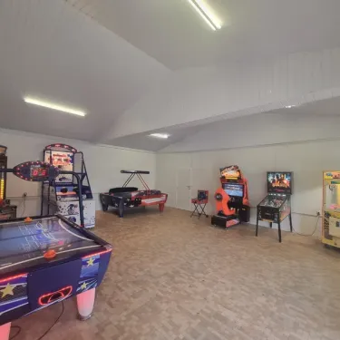 Salle de jeux avec table de billard, machine à air hockey et pinball au Camping Jardins de l'Atlantique