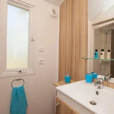 Salle de bain de Cottage Confort 3CH - 6P - Camping Le Paradis avec lavabo et miroir