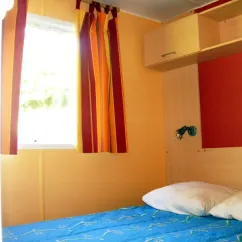 Chambre du Mobil Home 2/3 Pers. - Le Moulin de Serre avec lit et rideaux