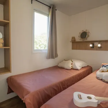 Chambre avec deux lits simples, étagères, miroir, guitare décorative