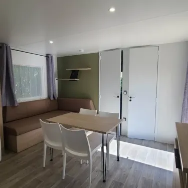 Mobil Home Confort 2 Chambres 4 Personnes TV - Le Domaine du Bois Coquet : coin repas et canapé
