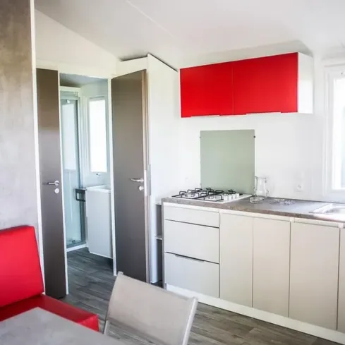 Mobil Home 2 Chambres 4 Personnes - Camping Le Bois des Écureuils, cuisine avec placards rouges et plan de travail