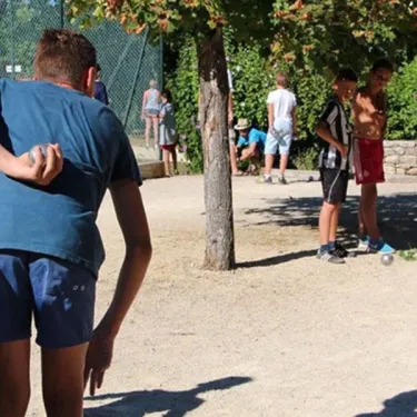 Camping l’Évasion : enfants jouant au ballon dans un espace extérieur ombragé