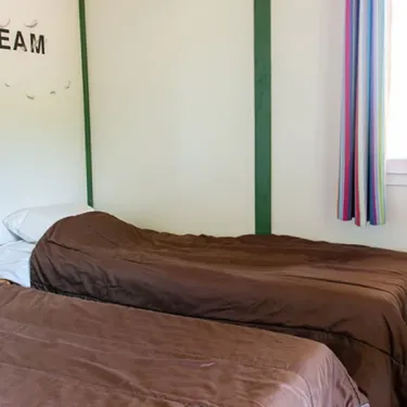 Chambre chalet Rocamadour avec deux lits simples et rideau coloré