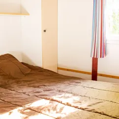 Chalet Pech Merle 2 Chambres 5 Personnes - Camping l'Évasion : lit double avec drap et rideau coloré