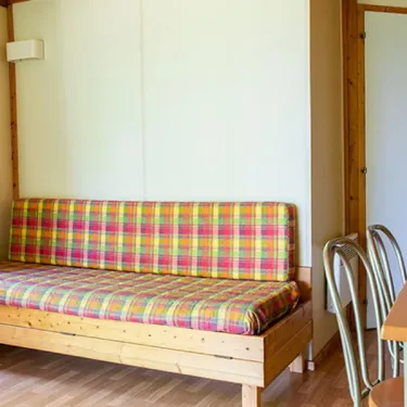 Chalet Sarlat 2 Chambres 5/7 Personnes - Camping l'Évasion : canapé-lit en bois avec couverture à carreaux