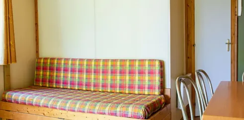 Chalet Sarlat 2 Chambres 5/7 Personnes - Camping l'Évasion : canapé-lit en bois avec couverture à carreaux