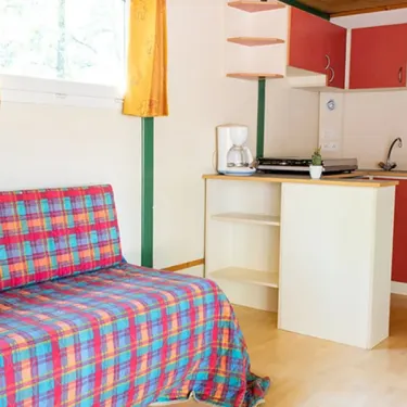 Salle de séjour et cuisine chalet Chalet Autoire 3 chambres 7 personnes Camping l'Évasion avec canapé et micro-ondes