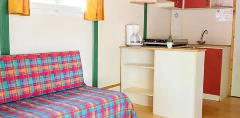 Salle de séjour et cuisine chalet Chalet Autoire 3 chambres 7 personnes Camping l'Évasion avec canapé et micro-ondes