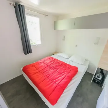 Mobil Home Premium 2 Chambres 4 Personnes et 1 Bébé - La Ferme : lit double avec couvre-lit rouge