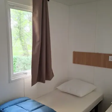 Chambre dans le mobil home L'Orchis des Marais, lit et fenêtre