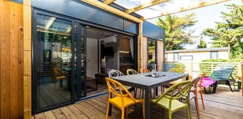 Terrasse extérieure du Mobil Home Hélios avec table, chaises colorées et toit en bois.