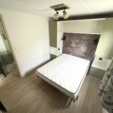 Chambre dans le bungalow Lagon 2 chambres, lit, mur en pierre, plafonnier