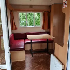 Mobil Home Jacinthe - Coin repas avec canapé et table en bois