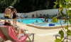 Personnes dans la piscine et sur les chaises longues au Camping Les Rives d'Auzon