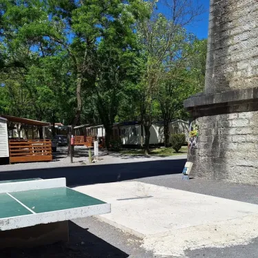 Table de ping-pong dans le camping Les Rives d'Auzon, entourée de mobil-homes et d'arbres