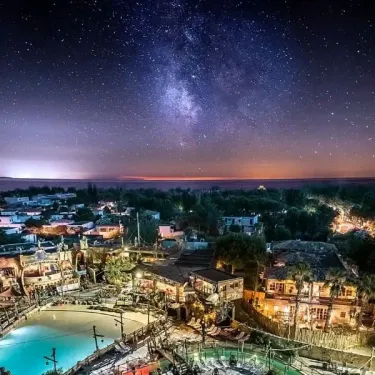 Vue nocturne du ciel étoilé au-dessus du camping avec lumières des bâtiments