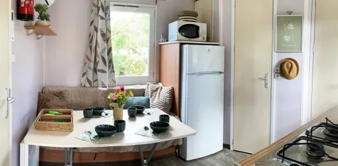 Mobil Home Malin 2CH 4P - Camping Val de Cesse : salle à manger avec table et frigo