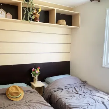Mobil Home Welcome 3CH 6P - Camping Val de Cesse : chambre avec deux lits et étagères