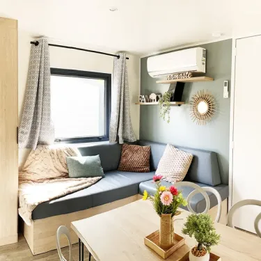 Mobil Home Premium 2CH 4P - Camping Val de Cesse : salon avec canapé-lit et table