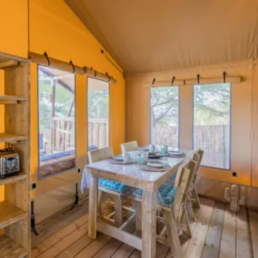 Camping Val de Cesse - Lodge River Premium 2CH 4P : salle à manger en tente avec table et chaises