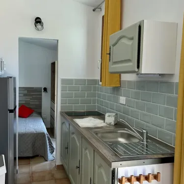 Cottage Premium 2 Chambres - Terrasse - 4 Pers. - Camping Village de Vacances Camboussel : cuisine avec lave-vaisselle et lit en arrière-plan