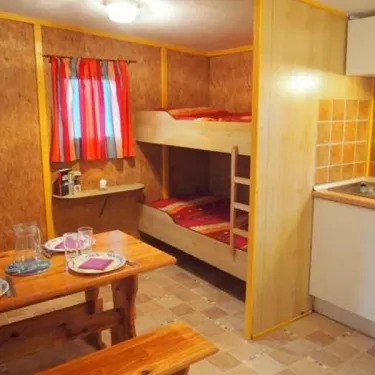 Chambre du bungalow Le Lavandin avec lits superposés, table et cuisine.
