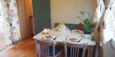 Table à manger avec chaises, couverts et plante dans le bungalow Le Lavandin.