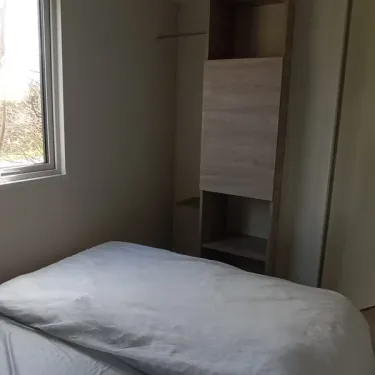 Mobil Home Studio 2P - Camping Les Peupliers : chambre avec lit et armoire