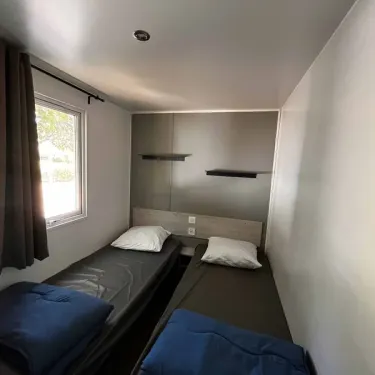 Chambre avec deux lits simples et rangements muraux dans Mobil Home Confort