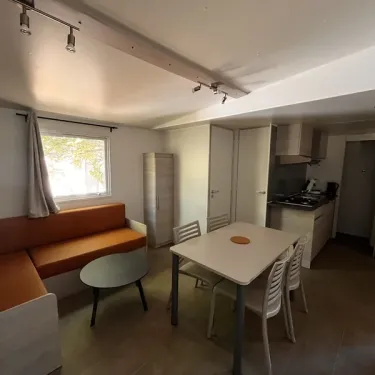 Salon et cuisine ouverte avec canapé, table à manger et cuisine - Mobil Home Confort 2 Chambres - Paradis Family