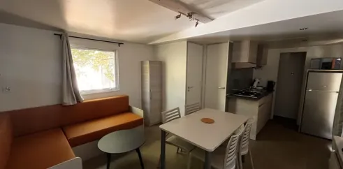 Salon et cuisine ouverte avec canapé, table à manger et cuisine - Mobil Home Confort 2 Chambres - Paradis Family