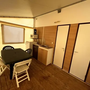 Intérieur de la tente avec cuisine et salle à manger dans le camping Paradis Family