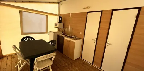Intérieur de la tente avec cuisine et salle à manger dans le camping Paradis Family