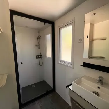 Salle de bain avec douche, lavabo et miroir dans Mobil Home Confort 3 Chambres - Paradis Family