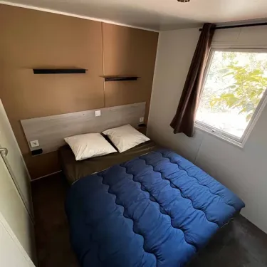 Chambre avec lit double et couvre-lit bleu dans Mobil Home Confort 3 Chambres - Paradis Family