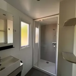 Salle de bain avec douche, lavabo et miroir dans le Mobil Home Confort 2 Chambres 4 Personnes Clim TV - Paradis Family les Rives de l'Hérault