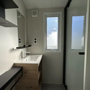 Salle de bain avec douche, lavabo et miroir dans le Mobil Home Confort 3 Chambres 6 Personnes Clim TV - Paradis Family les Rives de l'Hérault