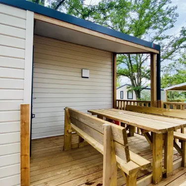 Terrasse en bois avec table et bancs devant Mobil Home Confort 3 Chambres 6 Personnes Clim TV - Paradis Family les Rives de l'Hérault
