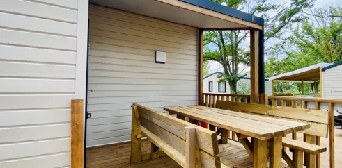 Terrasse en bois avec table et bancs devant Mobil Home Confort 3 Chambres 6 Personnes Clim TV - Paradis Family les Rives de l'Hérault