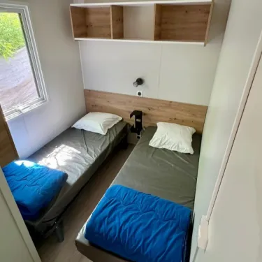 Chambre avec deux lits et étagères du Mobil Home Premium 4 Chambres 8 Personnes - Paradis Family les Rives de l'Hérault