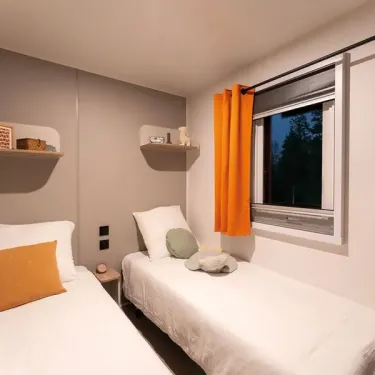 Mobil Home Confort 2 Chambres 4 Personnes - le Rompval : chambre avec lits et rideaux orange