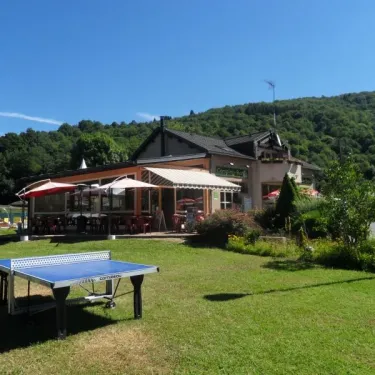 Table de ping-pong sur gazon devant le bâtiment du camping Le Moulin de Serre
